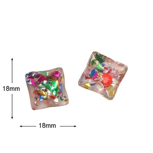 Macro shot of 18mm square resin charms with colorful glitter for DIY earring jewelry