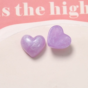 Close-up of heart-shaped glitter resin charms with pearlescent purple finish for DIY crafts
