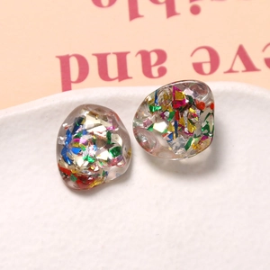 Macro view of irregular resin charms with colorful glitter and metallic foil flakes