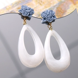 Detailed macro view of resin blue rose stud and hollow teardrop marble effect earrings