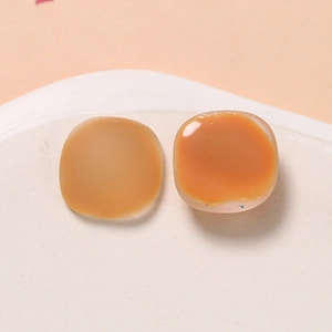 Macro view of matte pink and amber translucent resin square charms for DIY crafts