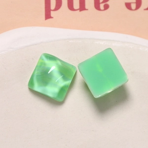 Detailed macro view of mint green resin square charms with a marbled cat-eye effect