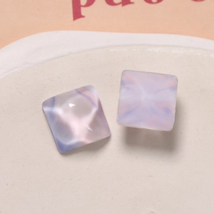Close-up of square resin earrings with purple marble texture on a white display tray