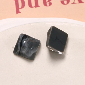 Macro shot of square resin pieces with black and grey marble texture on ceramic plate