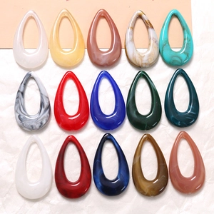 Macro detail of geometric teardrop resin charms with marble and ink texture patterns