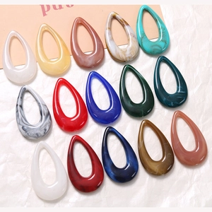 Flat lay of 13 colorful marble-textured teardrop resin charms for DIY jewelry making