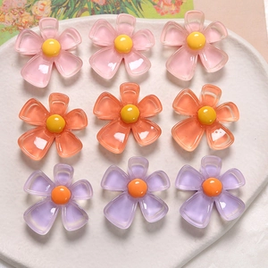 Vue à plat de breloques en résine de pétales colorés rose, orange et violet sur plateau