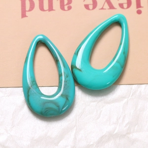 Macro shot of turquoise marble-patterned resin teardrop charms with hollow geometric design