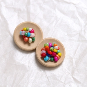 Detail view of colorful round wooden beads in natural wood trays for DIY clothing accessories