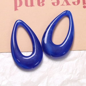 Macro detail of dark blue resin teardrop charms with white marble texture ink effect