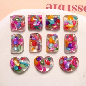 Colorful resin heart and square DIY charms with shell flakes on a ceramic tray