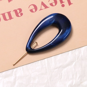 Detail of blue marble resin teardrop pendant with golden metal stud earring accessory