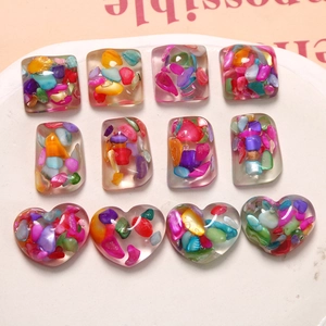 Macro shot of colorful resin heart and square DIY charms with iridescent shell flakes