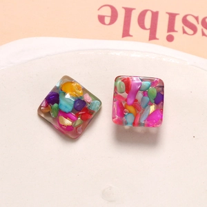 Macro shot of square resin earrings with colorful mosaic stone inlays and clear finish
