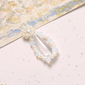 Detailed macro view of teardrop crystal pendant with woven pearls and blue moonstone beads