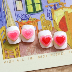 Dettaglio di ciondoli a cuore in resina 3D in rosa e rosso per nail art e fai da te