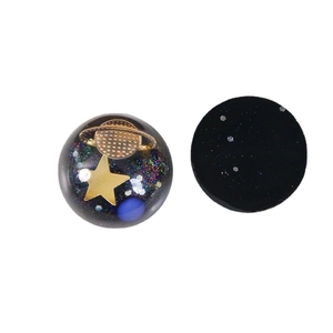 Boucles d'oreilles galaxie en résine avec saturne dorée et paillettes sur fond blanc