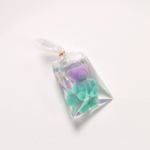 Detail of cute gradient purple and green resin bear charm in clear packaging