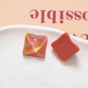 Dettaglio macro di ciondoli quadrati in resina con trama ondulata rosa e oro per artigianato