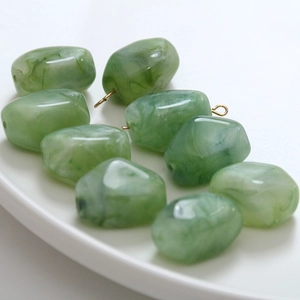 Close-up of green marble ink-pattern resin pendants with gold hanging loops for DIY jewelry