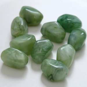 Close-up of polished green resin charms with marble pattern and pre-drilled holes