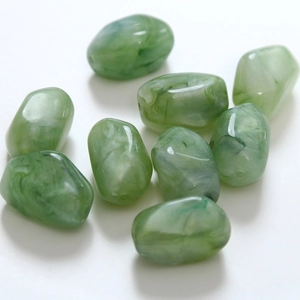 Detail shot of green marble pattern resin beads with smooth irregular pebble shape for DIY