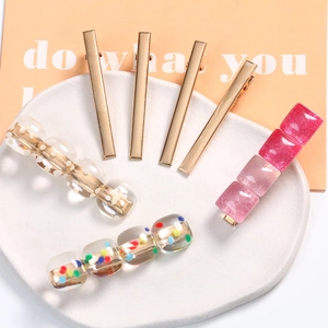 Detailed set of 7 gold metal hair clips with decorative acrylic beads on a white tray