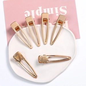 Set of six gold geometric hollow duckbill hair clips on a decorative ceramic tray