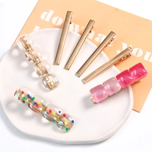 Set of 7 gold metal and resin hair clips featuring polka dots and glitter in a ceramic dish