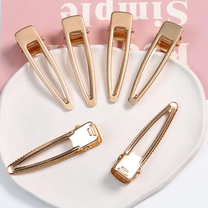 Set of six gold geometric alloy duckbill hair clips displayed on a white tray