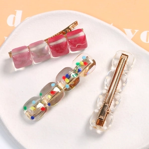 Three resin alligator hair clips with pink marble and polka dot patterns on a tray