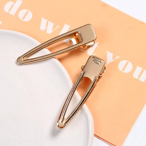 Detailed macro view of two gold geometric hollow triangle alloy duckbill hair clips
