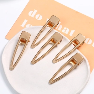Set of 5 minimalist gold-finish geometric hollow alloy hair clips on a ceramic plate