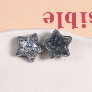 Detailed view of two dark grey glitter resin star charms for DIY jewelry and hair clips