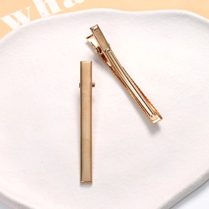 Macro detail of glossy golden metal duckbill clips on an elegant stone tray display