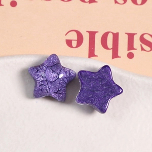 Close-up of purple glitter star resin accessories with moon detail in a ceramic bowl