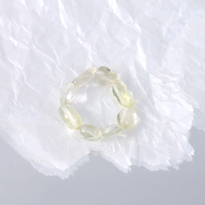 Macro shot of oval translucent yellow gemstone beads on an elastic minimalist ring