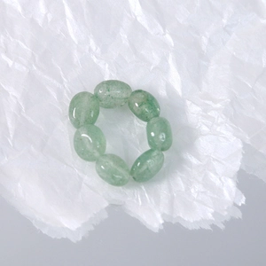 Detail of stretch ring made with green oval natural stone beads on crumpled paper