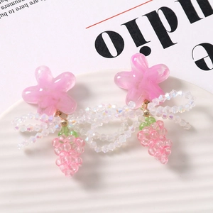 Detailed close-up of pink resin flower and grape-shaped beaded charm on a white tray