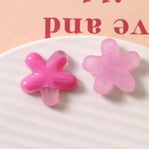 Macro shot of pink ink-wash resin five-petal flower DIY charms in a white striped dish