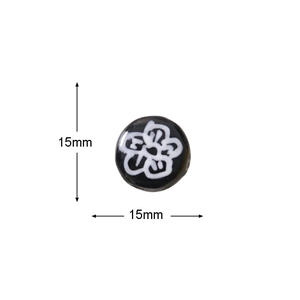 Macro detail of a 15mm flat round glass bead with hand-painted white plum flower pattern