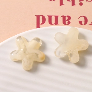 Macro detail of cream yellow resin flower charms with marble texture for DIY jewelry making