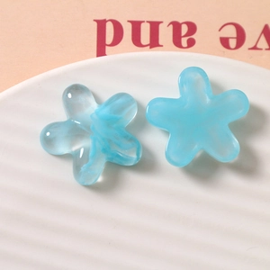 Macro shot of two light blue translucent resin five-petal flowers for DIY jewelry making