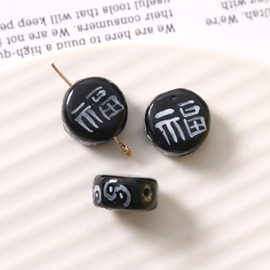 Detail of black glass beads with white Fu character and gold pin for DIY jewelry making