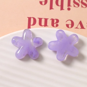 Macro shot of purple translucent resin flower charms with marble texture on ceramic tray