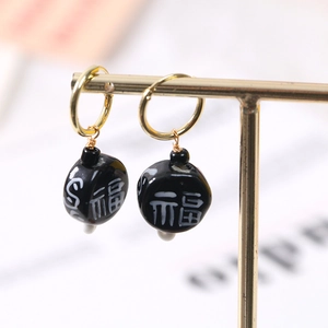 Detailed macro view of golden hoop earring with black Fu character bead pendant