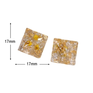 Detailansicht der 17 mm quadratischen Resin-Ohrstecker mit Goldfolie und gelben Trockenblumen