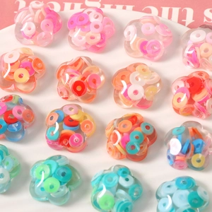 Macro shot of colorful floral resin charms with glittering sequins for DIY jewelry making