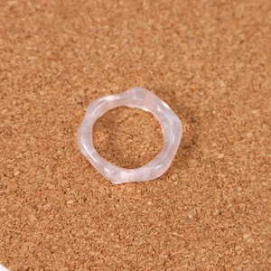 Détail d'une bague irrégulière en résine translucide avec une texture blanc nacré