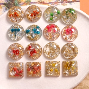 Makroaufnahme von 16 DIY-Resin-Anhängern mit echten Trockenblumen und Goldfolie